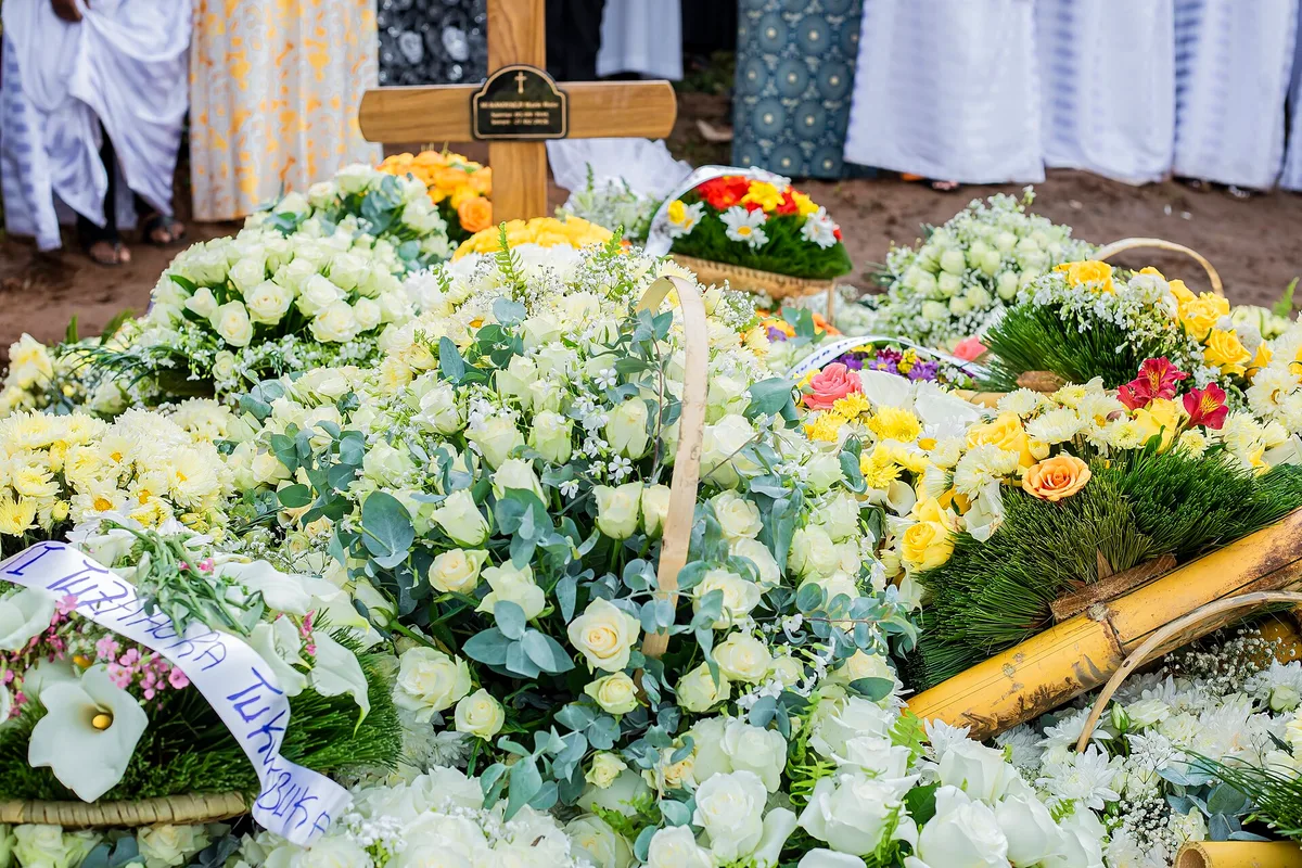 Flores brancas e amarelas sobre sepultura com cruz de madeira durante um funeral cristão